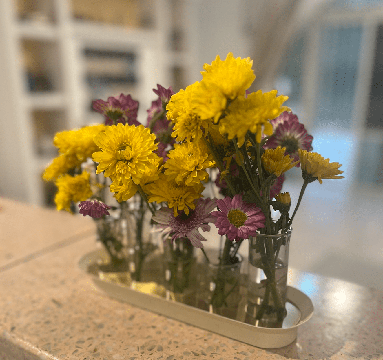 Yellow and magendta flowers in a low bud vase arrangement.